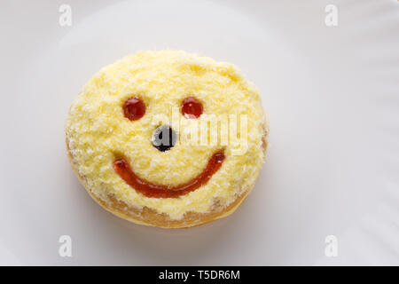 Smiley ciambella su una piastra bianca, ciambella con sfondo bianco Foto Stock
