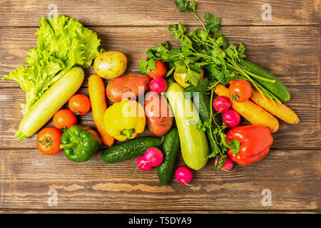 Raccolto freschi maturi Zucchine Ortaggi cetriolo pepe verdi distese su un sfondo di legno. Cibo sano per la mietitura. Foto Stock
