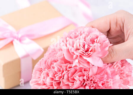 Concetto di Design - Donna dando i garofani bouquet su marmo sfondo bianco, vista dall'alto, copia spazio, vicino, mock up. Festa della mamma idea ispirazione. Foto Stock