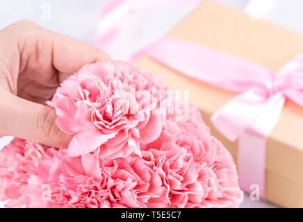 Concetto di Design - Donna dando i garofani bouquet su marmo sfondo bianco, vista dall'alto, copia spazio, vicino, mock up. Festa della mamma idea ispirazione. Foto Stock