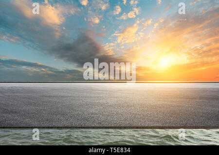 Gara di asfalto via terra e fiume con belle nuvole al tramonto Foto Stock