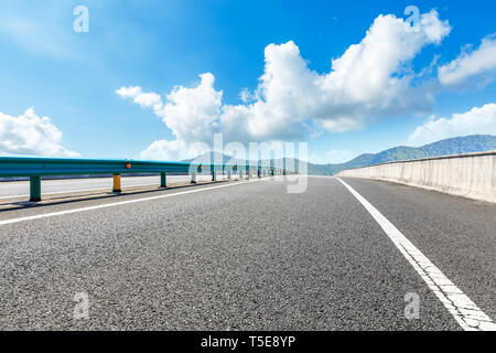 Svuotare strada asfaltata e montagne con cielo blu in una giornata di sole Foto Stock