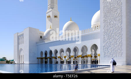 Abu Dhabi, Emirati Arabi Uniti, 7 Febbraio 2019: tranquilla scena, famoso marmo bianco Sheikh Zayed Grande Moschea di Abu Dhabi. Due uomini sono attraversamento t Foto Stock