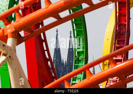 Roller Coaster con loop su la fiera sulle rive del fiume Reno, nel distretto cittadino Deutz, vista sulla cattedrale di Colonia, Germania. Achterbahn Foto Stock