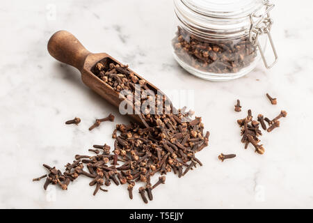 Spice i chiodi di garofano e scoop di legno sulla tavola di marmo. Syzygium aromaticum Foto Stock