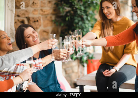 Piccolo gruppo di amici di sesso femminile che celebra con un bicchiere di champagne. Essi stanno facendo un brindisi celebrativo. Foto Stock