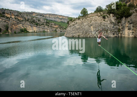 HUESCA, Spagna - 16 maggio: un uomo che fa highline al di sopra di una lac, Huesca, Puente de Montañana, in Spagna il 16 maggio 2014 in Puente de Montañana, Spagna. Foto Stock