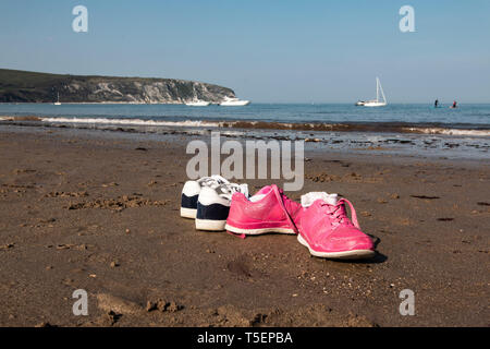 Due paia di scarpe a sinistra sulla sabbia a Swanage beach, REGNO UNITO Foto Stock