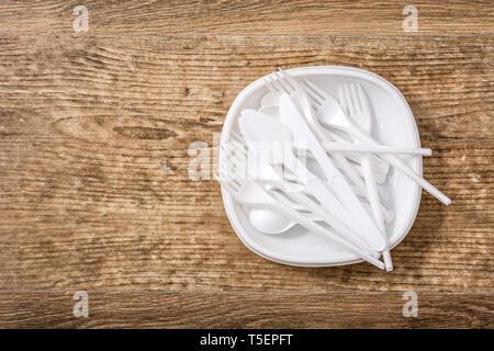 Monouso stoviglie di plastica su sfondo di legno. Vista dall'alto. Copyspace Foto Stock