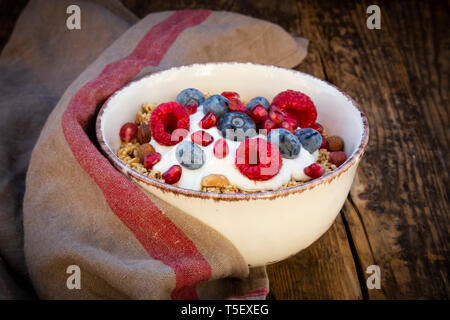 Ciotola di muesli con yogurt greco, schioccato la quinoa, Lamponi Mirtilli e i semi di melograno, dal di sopra Foto Stock