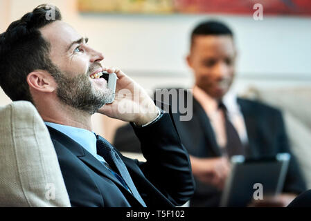 Imprenditore utilizzando smart phone in HALL HOTEL Foto Stock