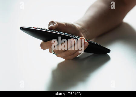 Mano che tiene il controllo remoto Foto Stock