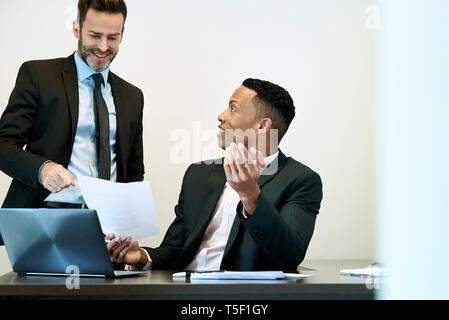 Imprenditori per discutere il documento alla scrivania in ufficio Foto Stock