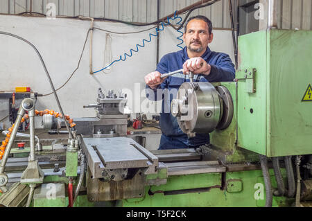 Colletto blu operatore macchina lavora con un tornio in una fabbrica. Foto Stock