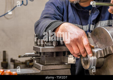 Colletto blu operatore macchina lavora con un tornio in una fabbrica. Foto Stock