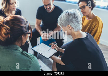 Multi-etnico personale di ufficio seduta avente riuniti insieme. Business donna che spiega la strategia per il team. Foto Stock