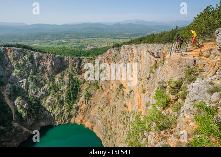 IMOTSKI, Croazia - 02 maggio: un uomo con un paracadute e con i suoi amici saltando al di sopra del lago rosso, Split-Dalmatia, Imotski, Croazia il Maggio 02, 2018 a Imotski, Croazia. Foto Stock