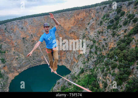 IMOTSKI, Croazia - 03 maggio: un uomo che cammina su un highline sopra il Lago Rosso, Split-Dalmatia, Imotski, Croazia il Maggio 03, 2018 a Imotski, Croazia. Foto Stock