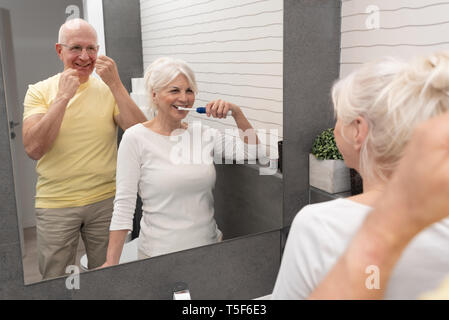 Le persone anziane mediante spazzolatura dei denti e il filo interdentale. La mattina in bagno Foto Stock