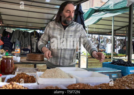 Zemun, Serbia, 19 Aprile 2019: venditore in piedi dietro la sua frutta secca e noci stand ad un mercato verde Foto Stock