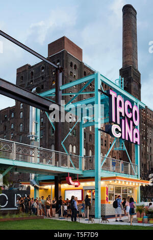 Ristorante Tacocina contro lo sfondo del Domino ex fabbrica di zucchero. Domino Park, Brooklyn, Stati Uniti. Architetto: James angolo opera sul campo Foto Stock