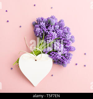 Molla fiori lilla e a forma di cuore tag su sfondo rosa. Mockup etichetta per felice giornata della madre, Donna, compleanno. Foto Stock