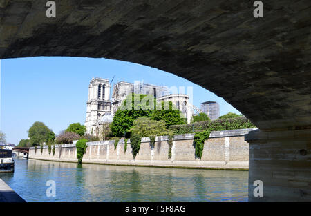 Parigi, Francia - 19 Aprile 2019: la struttura danneggiata della cattedrale di Notre Dame incorniciata dal Pont de l'Archeveche attraverso il Fiume Senna. Foto Stock