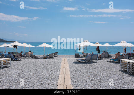 I villeggianti rilassarsi a prendere il sole sotto gli ombrelloni sulla spiaggia da Elies hotel nel villaggio di Kardamyli nelle mani della penisola del Peloponneso, Grecia Foto Stock