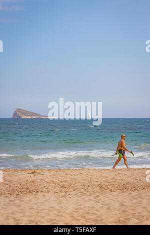 Uomo anziano in tronchi passeggiate lungo la riva del mare sulla spiaggia di Benidorm Spagna Foto Stock