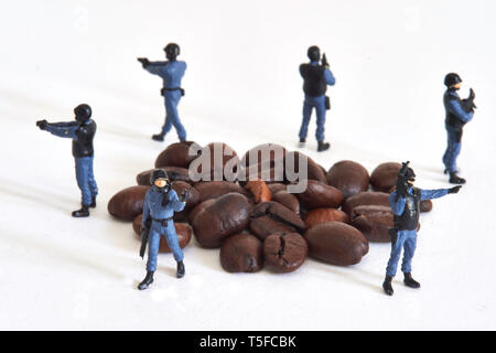 Figurine che rappresentano gli ufficiali di polizia che circonda i chicchi di caffè: protezione e fissaggio globale del mercato del caffè.Caption locale *** Foto Stock