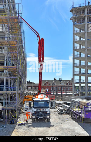 Euromix consegna camion Truck & driver la colata di cemento in verticale del braccio di pompaggio rig a livello del tetto su confinata costruzione cantiere London REGNO UNITO Foto Stock