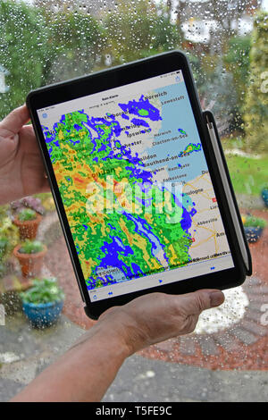 In tempo reale radar a colori sovrapponendo i dati di pioggia sulla mappa locale di bagnato sulla finestra home mani tenendo ipad Apple pro tablet allarme pioggia app Essex REGNO UNITO Foto Stock