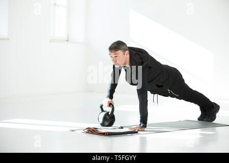 L uomo che sta facendo il suo regime fitness, bollitore facendo bell push-up Foto Stock