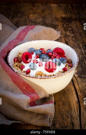 Ciotola di muesli con yogurt greco, schioccato la quinoa, Lamponi Mirtilli e i semi di melograno, dal di sopra Foto Stock