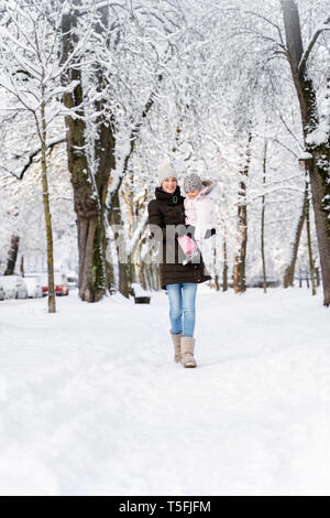 Felice madre camminando con la figlia nel paesaggio invernale Foto Stock