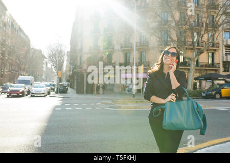 Donna elegante parlando al cellulare nella città Foto Stock