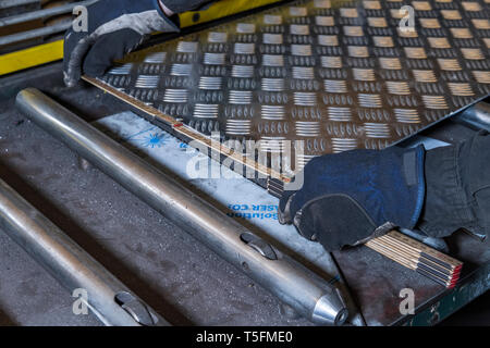 Due mani lavorando con acciaio e con un coltello in acciaio. Foto Stock