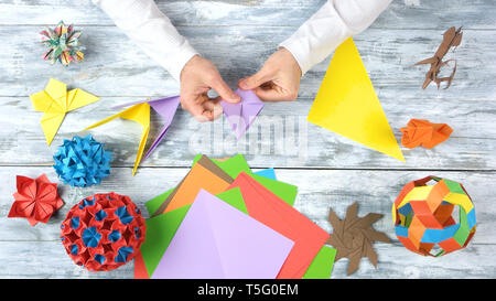 Le mani facendo origami rondini. Foto Stock