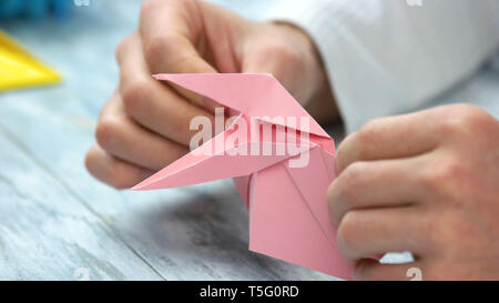 Close up uomo rosa di piegatura origami rana. Foto Stock