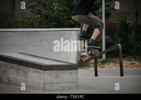 I pattinatori di eseguire trick in parco pubblico facendo un Ollie giù per le scale Foto Stock