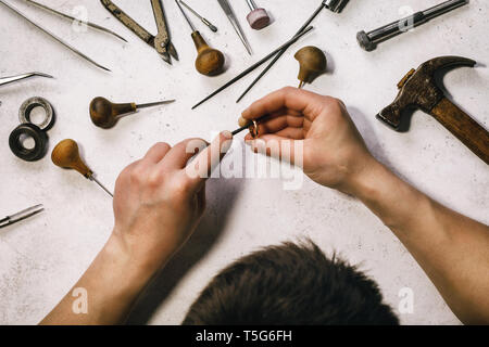 Il gioielliere leviga il anello d'oro al suo posto di lavoro. Vista dall'alto su attività di laboratorio Foto Stock