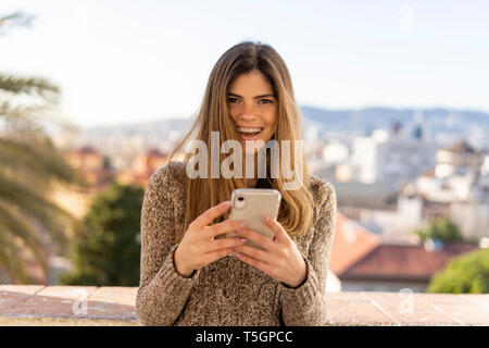 Ritratto di ridere giovane donna azienda telefono cellulare Foto Stock