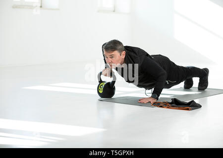 L uomo che sta facendo il suo regime fitness, bollitore facendo bell push-up Foto Stock
