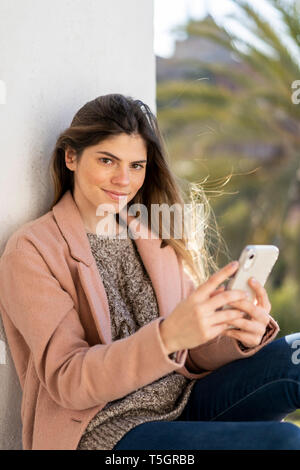 Ritratto di sorridente giovane donna azienda telefono cellulare Foto Stock