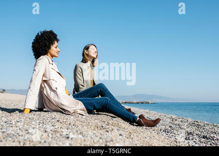 Due amici seduti sulla spiaggia godendosi il tempo libero Foto Stock