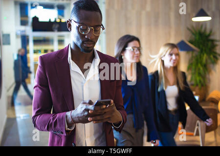 La gente di affari a piedi nella hall dell'albergo, l'uomo utilizza lo smartphone Foto Stock