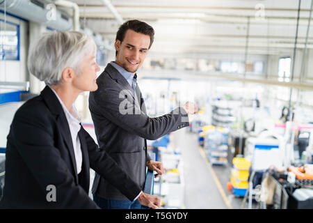 Imprenditore sorridente parlando a senior imprenditrice in fabbrica Foto Stock