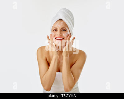 Giovane donna l'applicazione di crema per il viso sul suo viso Foto Stock
