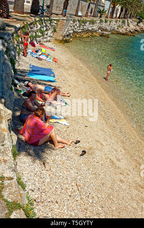 Stretto di sabbia grossolana beach; persone; seawall, vacanze; relax, acqua mare Adriatico; Dalmazia; la città di Korcula; Croazia; Europa; estate, verticale Foto Stock