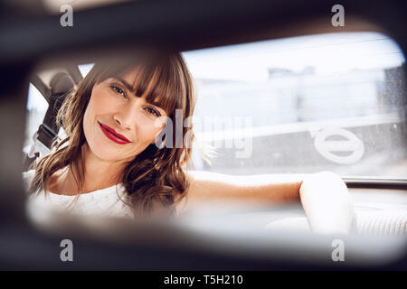 Bella donna seduta in auto d'epoca Foto Stock